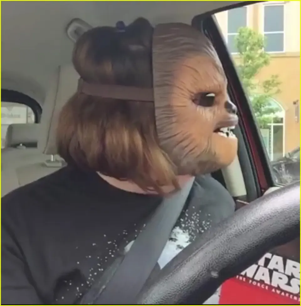 Candace Payne laughing in her car while wearing an electronic Chewbacca mask