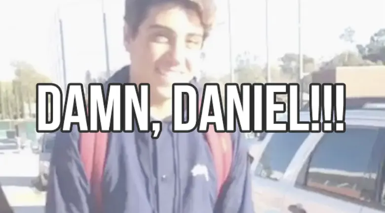 Smiling teenage boy in a navy jacket with a red backpack in a school parking lot, captioned "Damn, Daniel!!!"