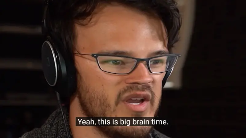 Video still of a bearded man in glasses and headphones, subtitled "Yeah, this is big brain time."